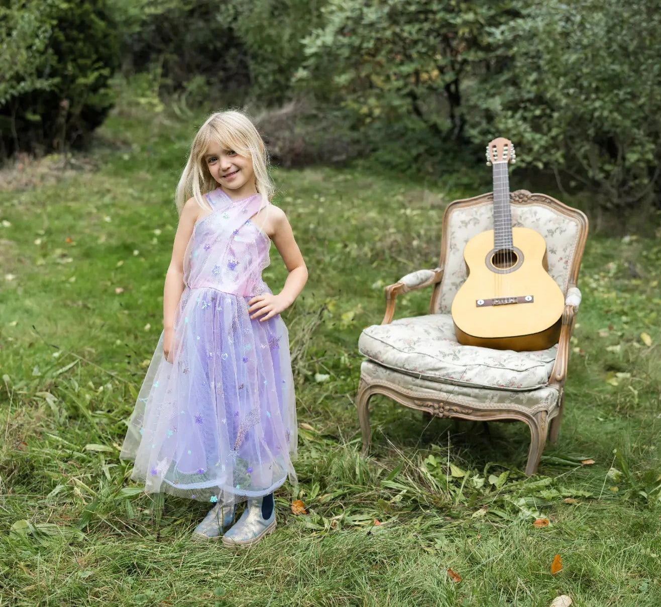 young girl standing in field by a guitar