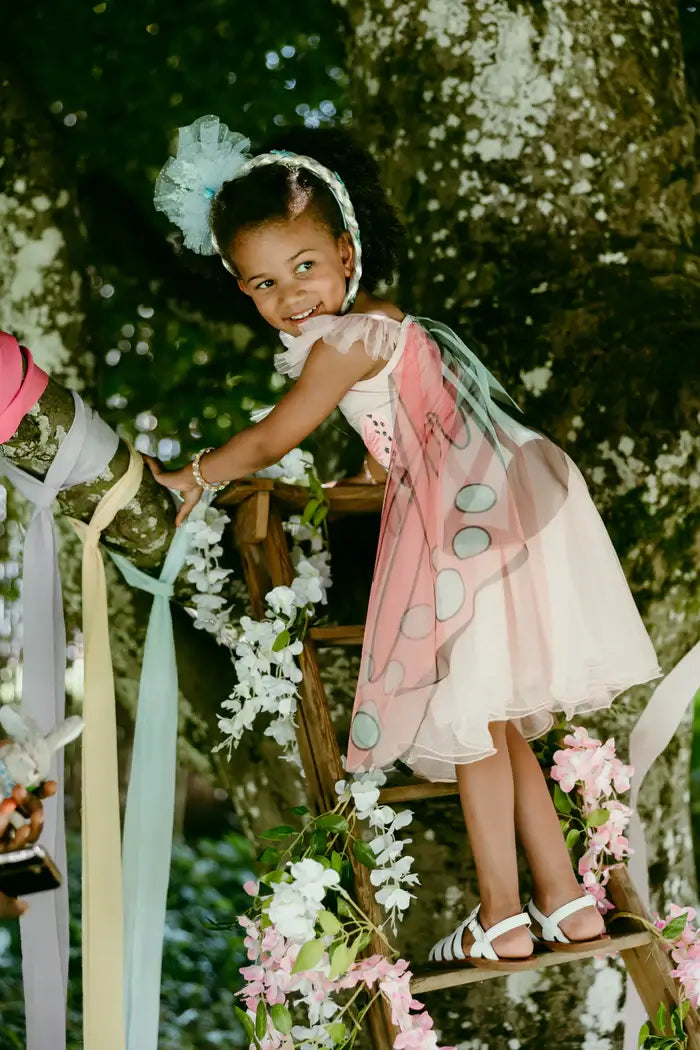 young girl playing in a tress house dressed as a fairy