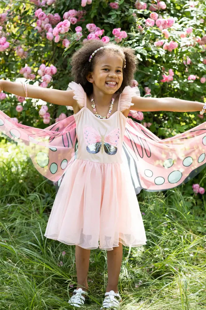 Young girl holding her wings on the butterfly fairy dress