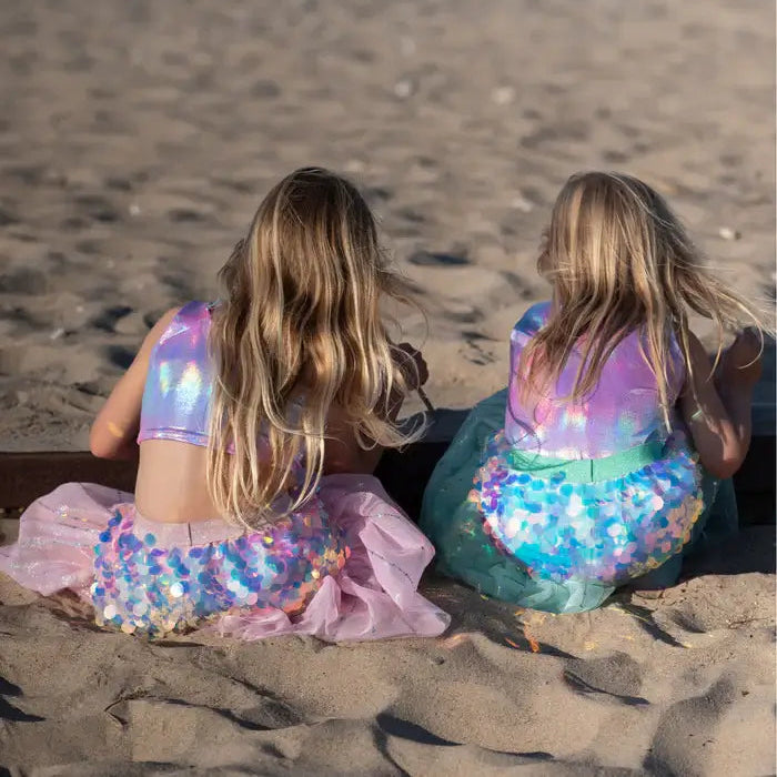 two girls dressed up as mermaids on the beach