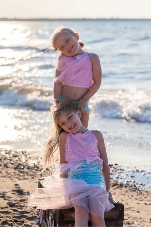 2 girls playing on beach dressed as mermaids