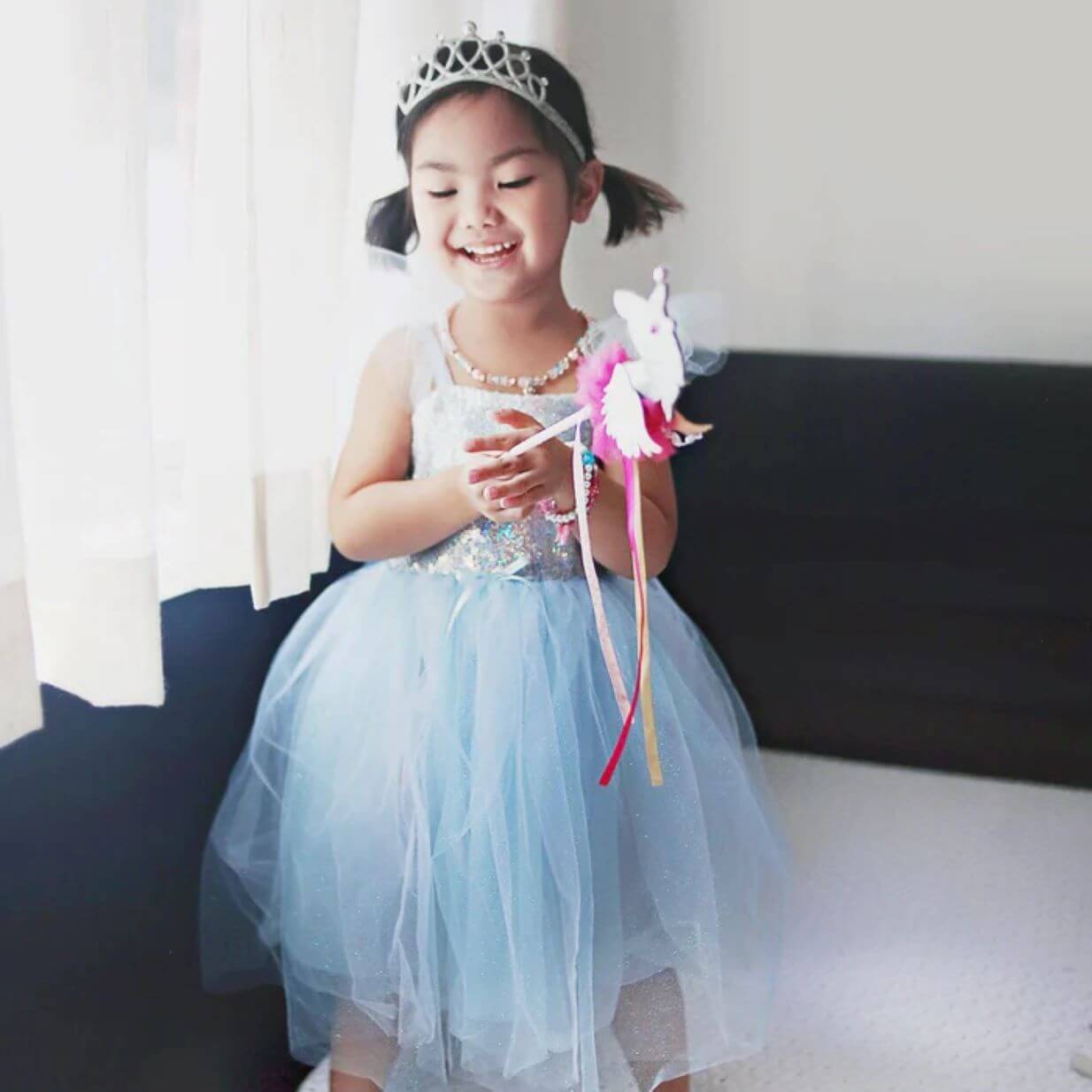 Small girl in blue sequinned party dress with silver tiara and pink wand