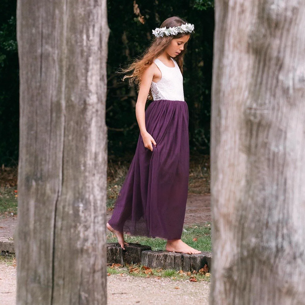 Girl wearing purple flower girl dress walking in a park