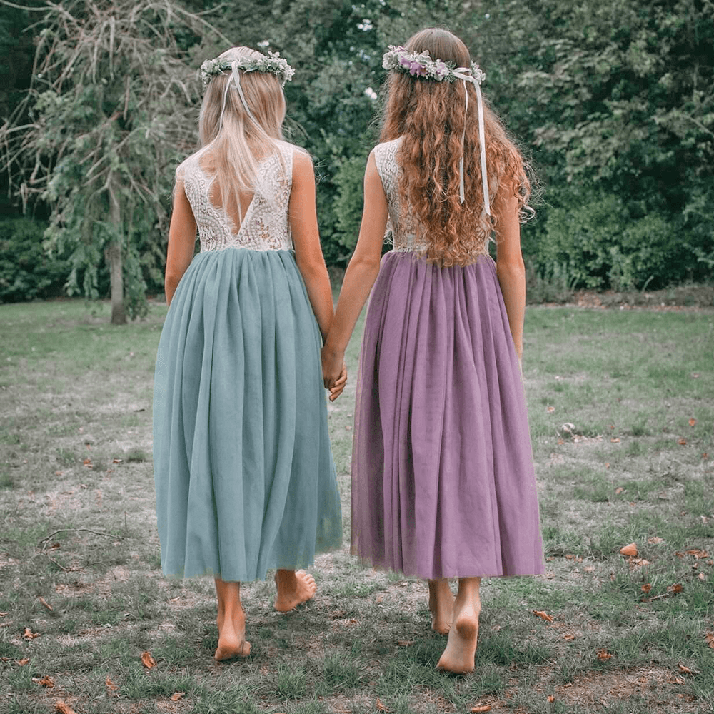 Two flower girls holding hands in a garden