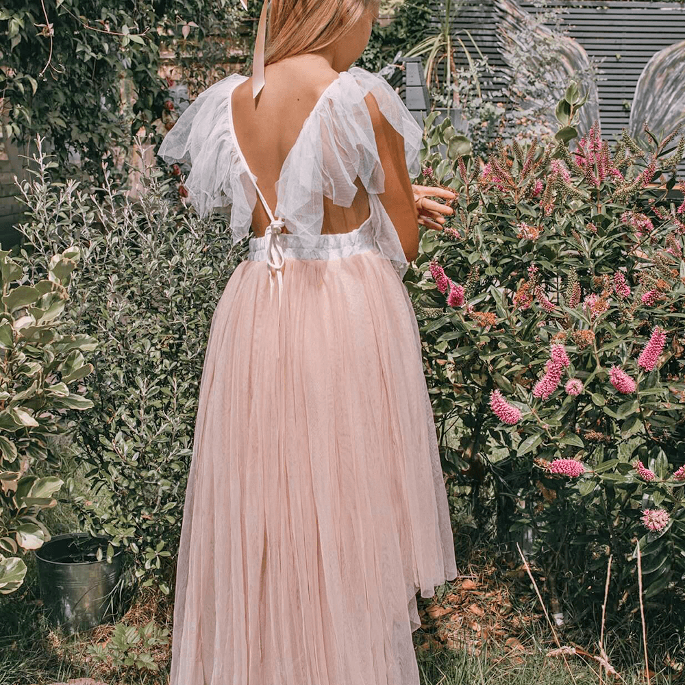 girl in garden wearing a blush coloured flower girl dress