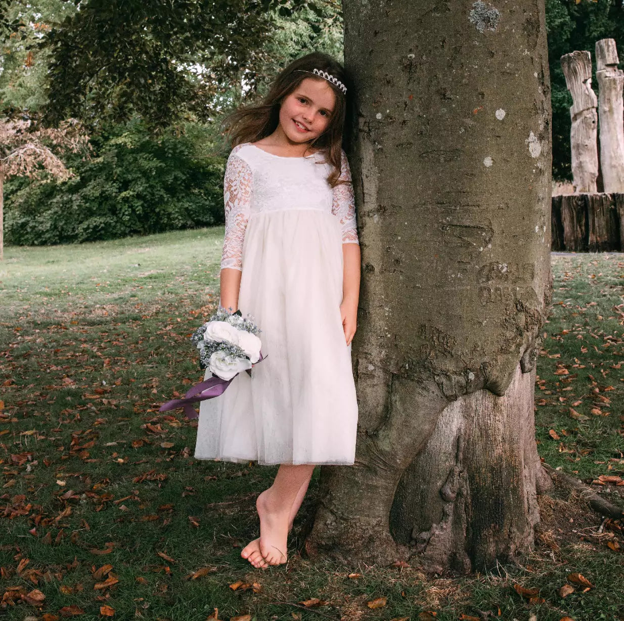 flower girl leant against tree