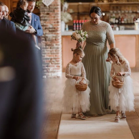 oung flower girls walking down the isle in bohemian spirit flower girl dresses