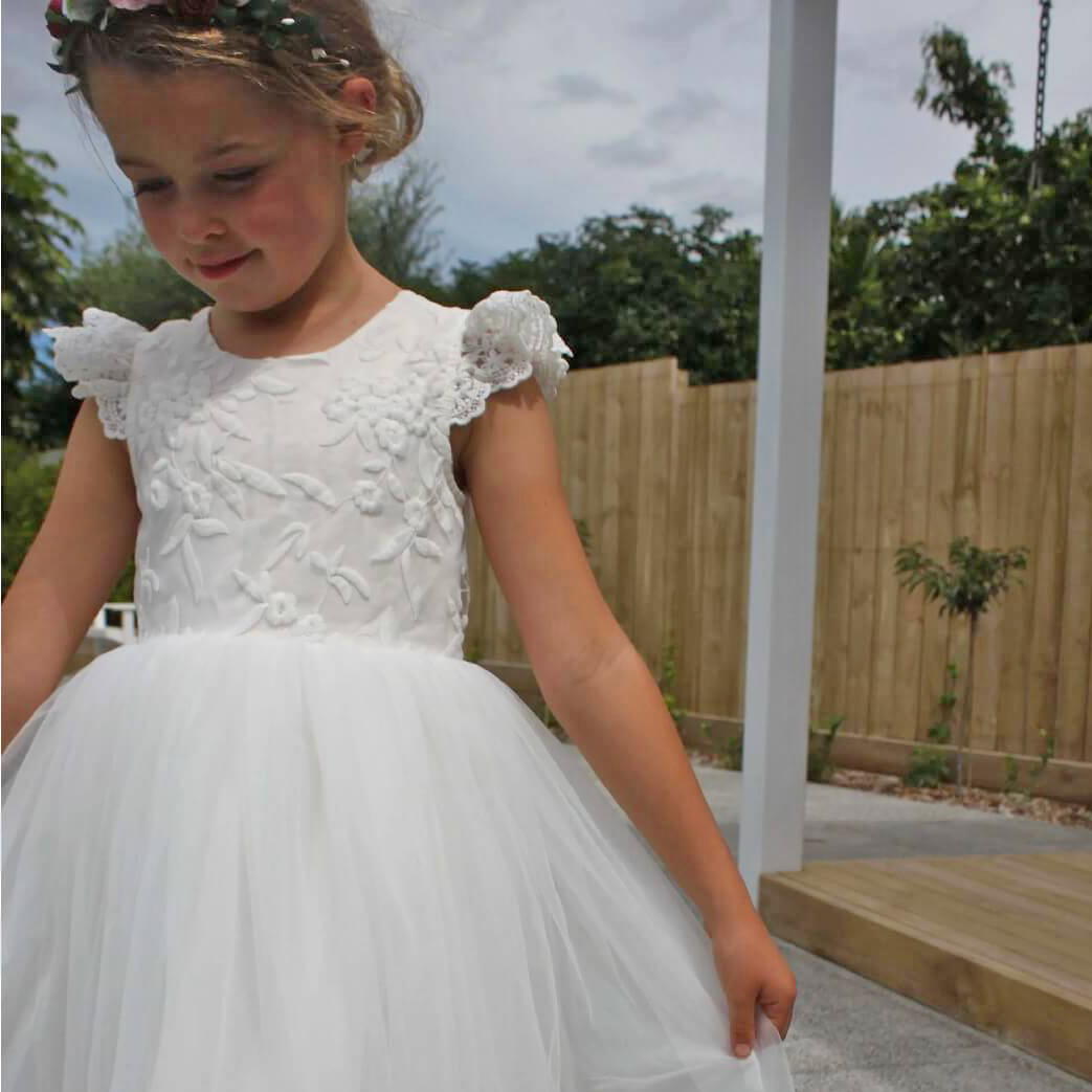Gril in a garden wearing. flower girl dress