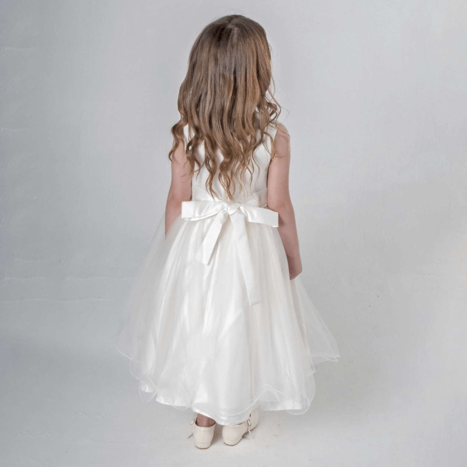 Girl wearing ivory party dress with bow on back