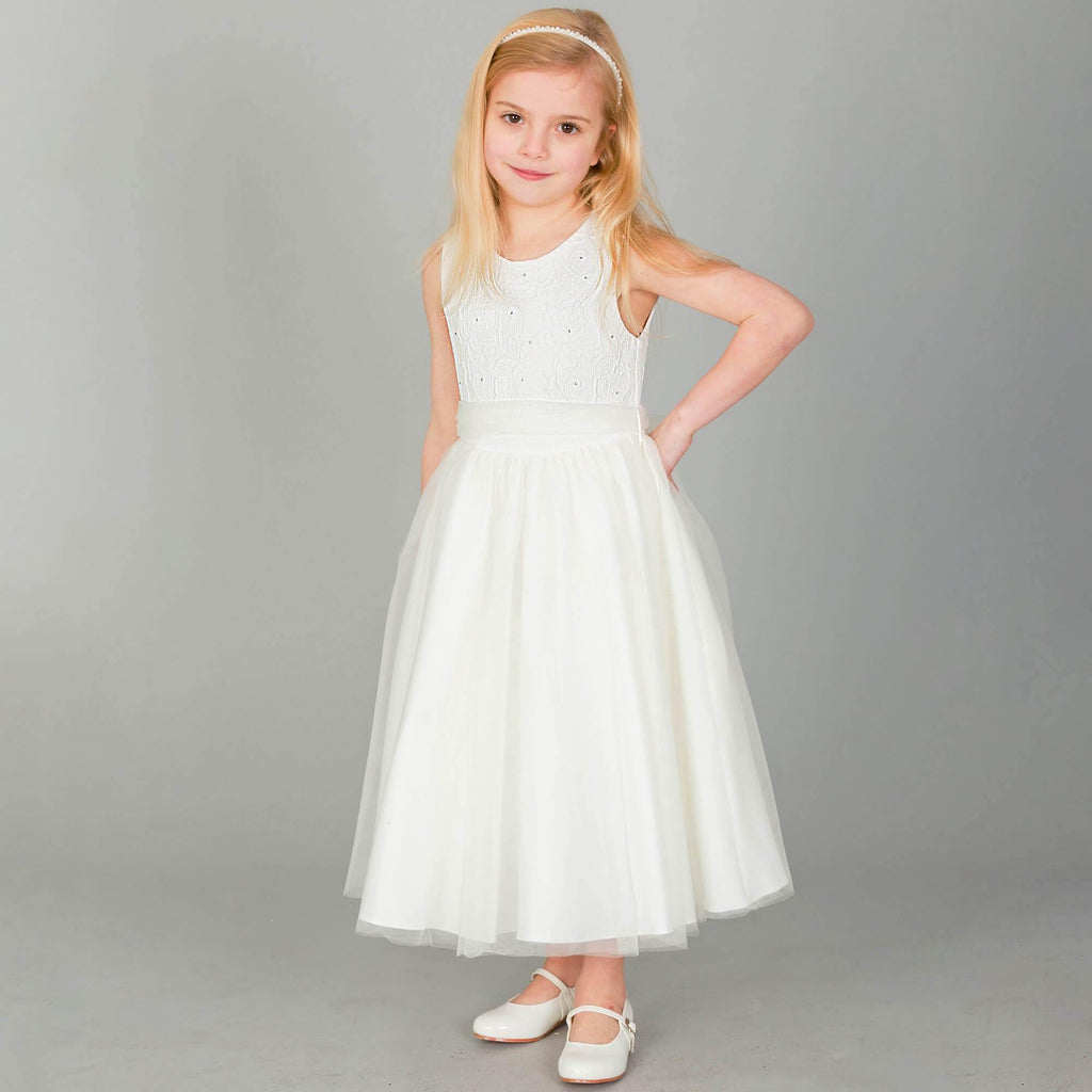 Blonde girl wearing ivory coloured party dress and whit party shoes