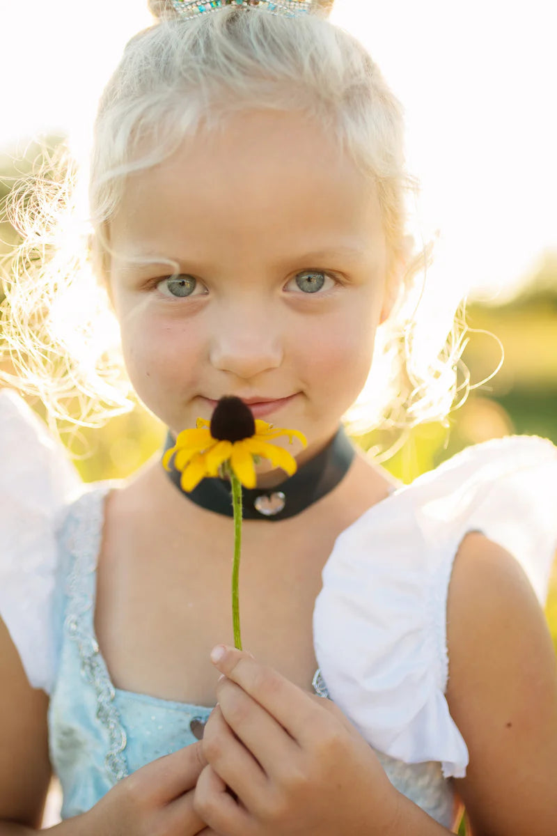 Young girl holding a yellow flower with a blurred natural background