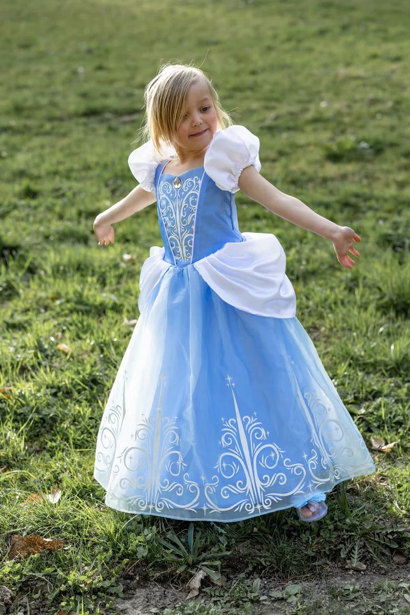 Child in a blue dress with white embroidery standing on grass