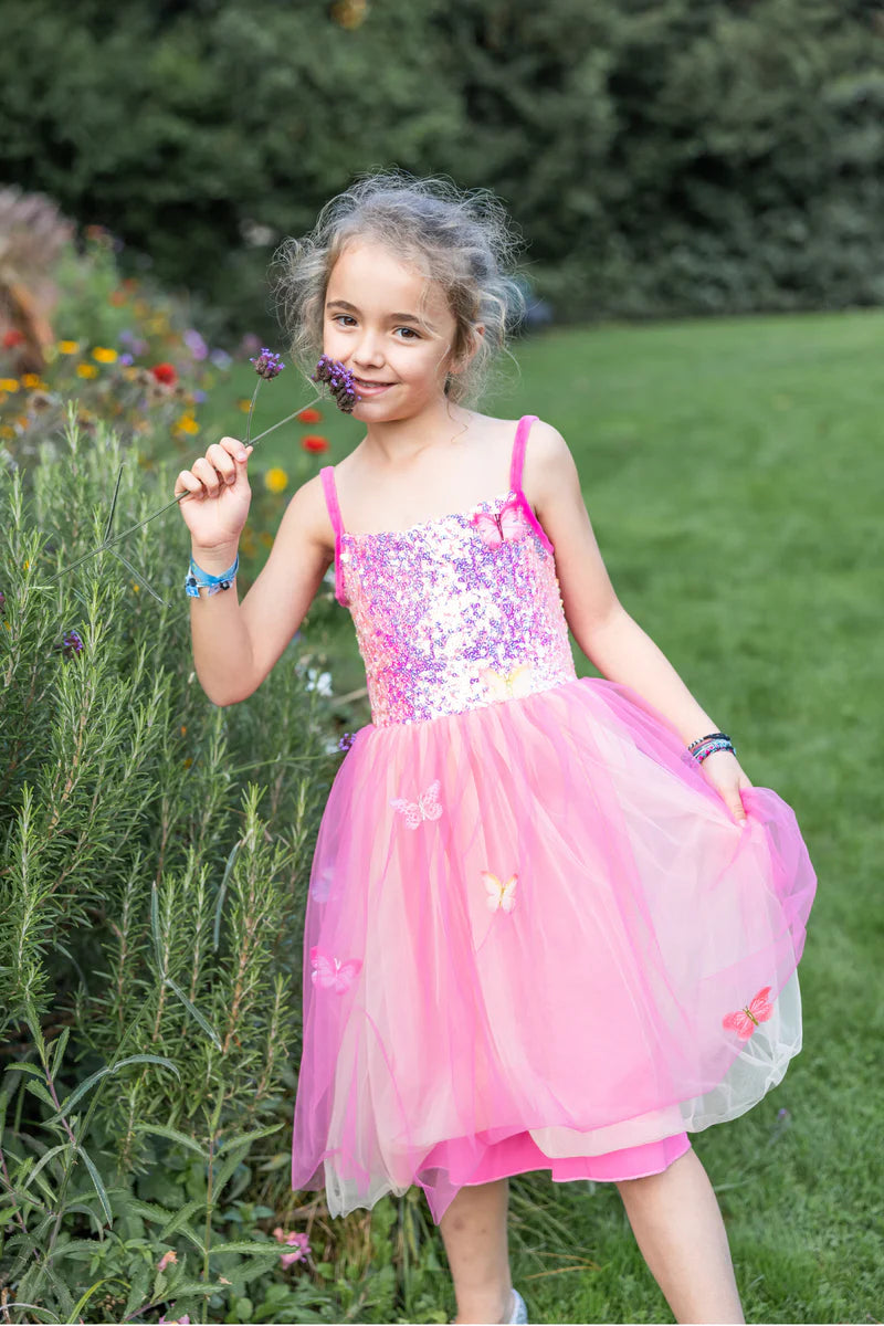 Young girl in a pink dress holding a flower in a garden