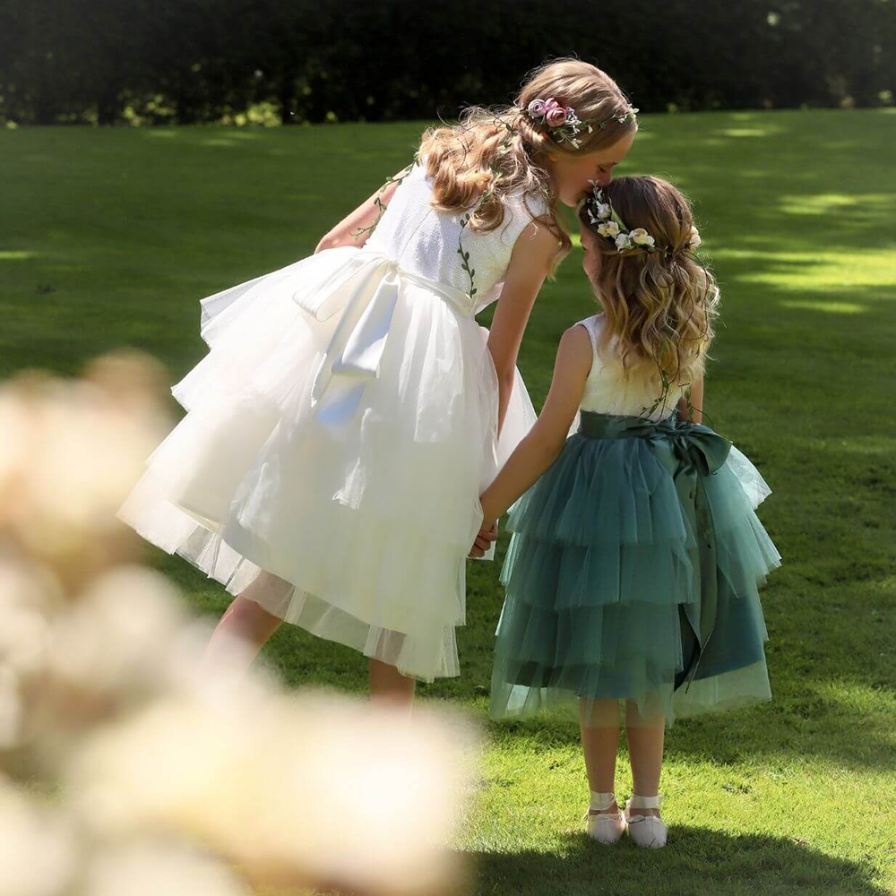 Two girls in a garden holding hands in flower girl dresses