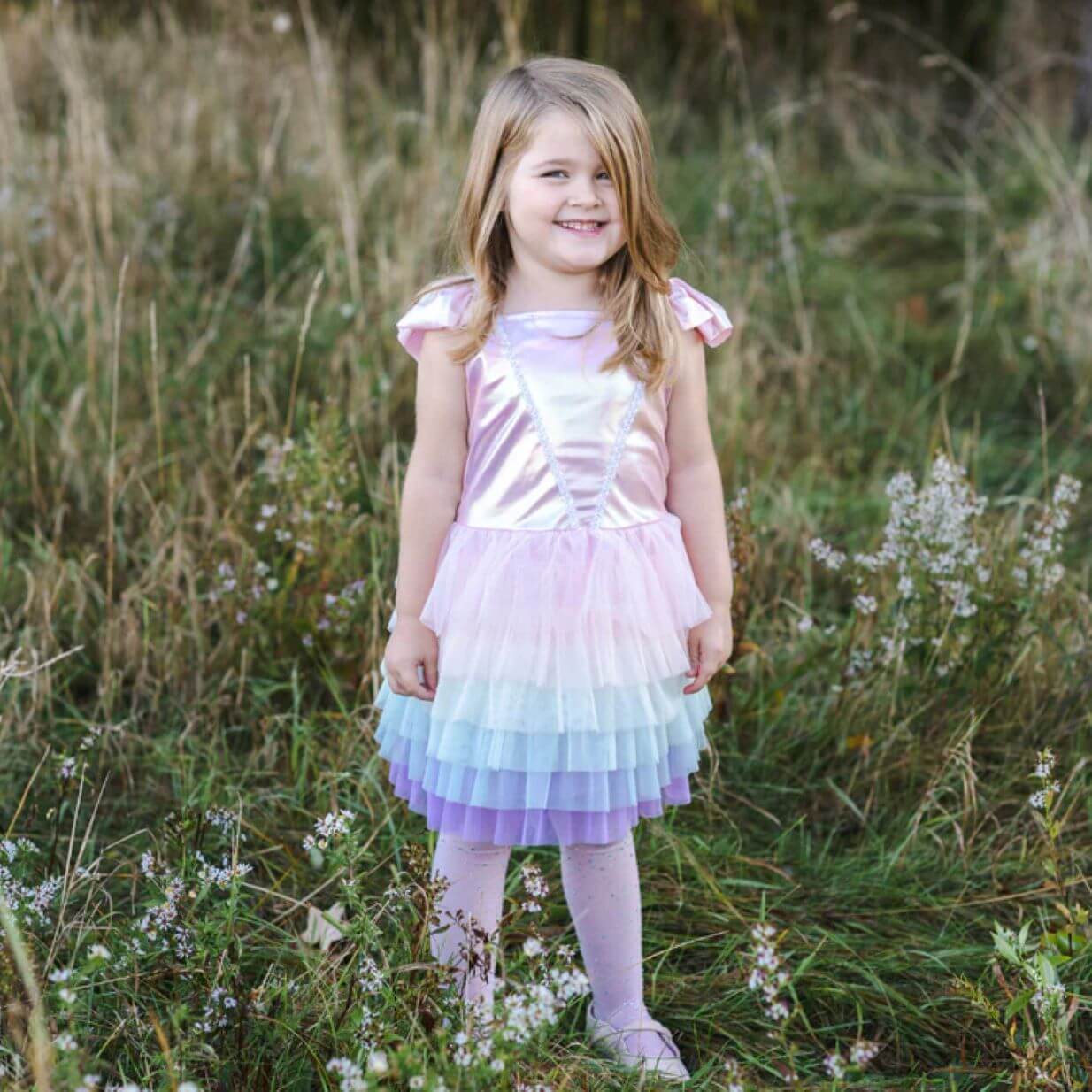 Little girl in field with dress with pink satin bodice and rainbow pastel coloured tulle tutu skirt