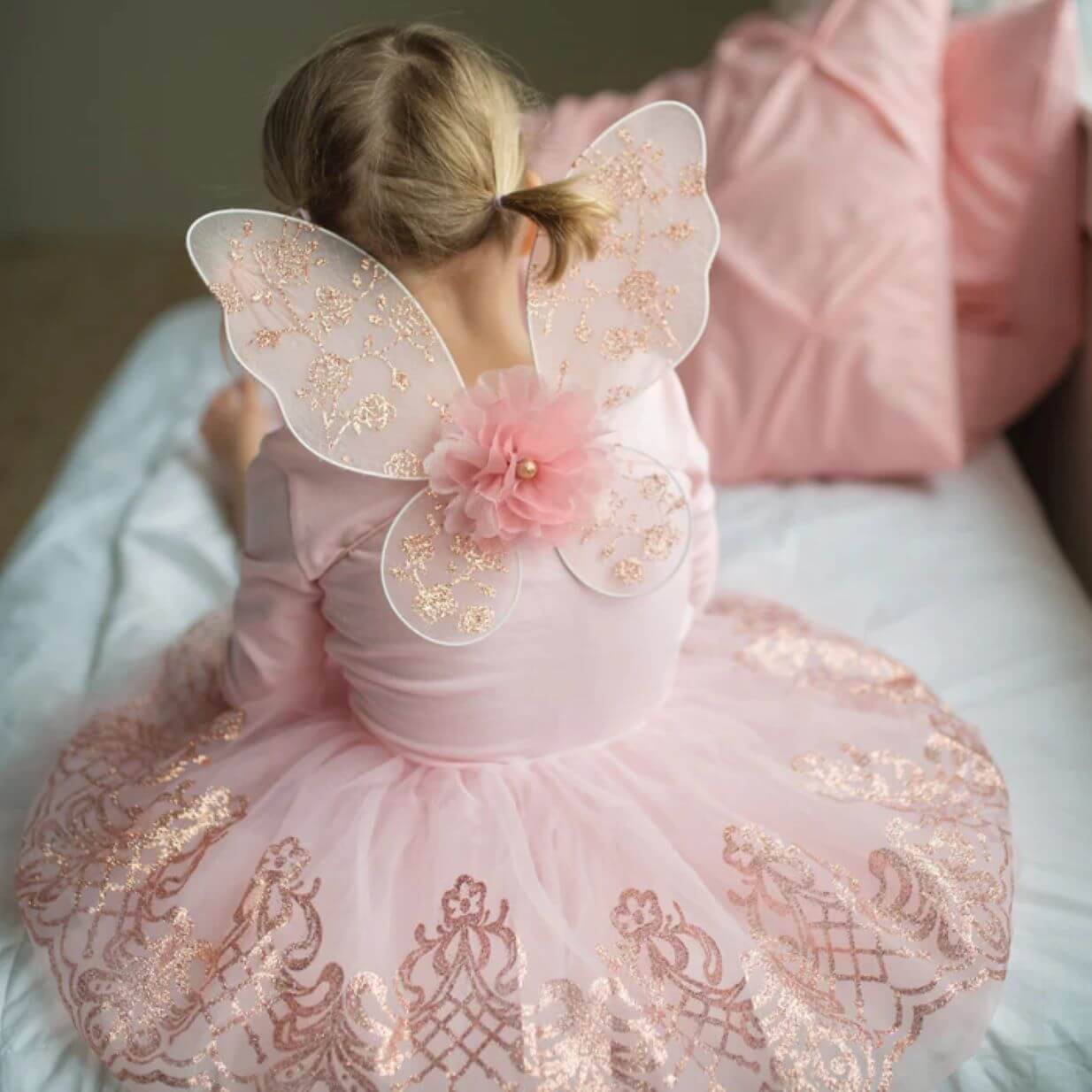 Back view of young girl in pink glittered fairy wings and matching skirt