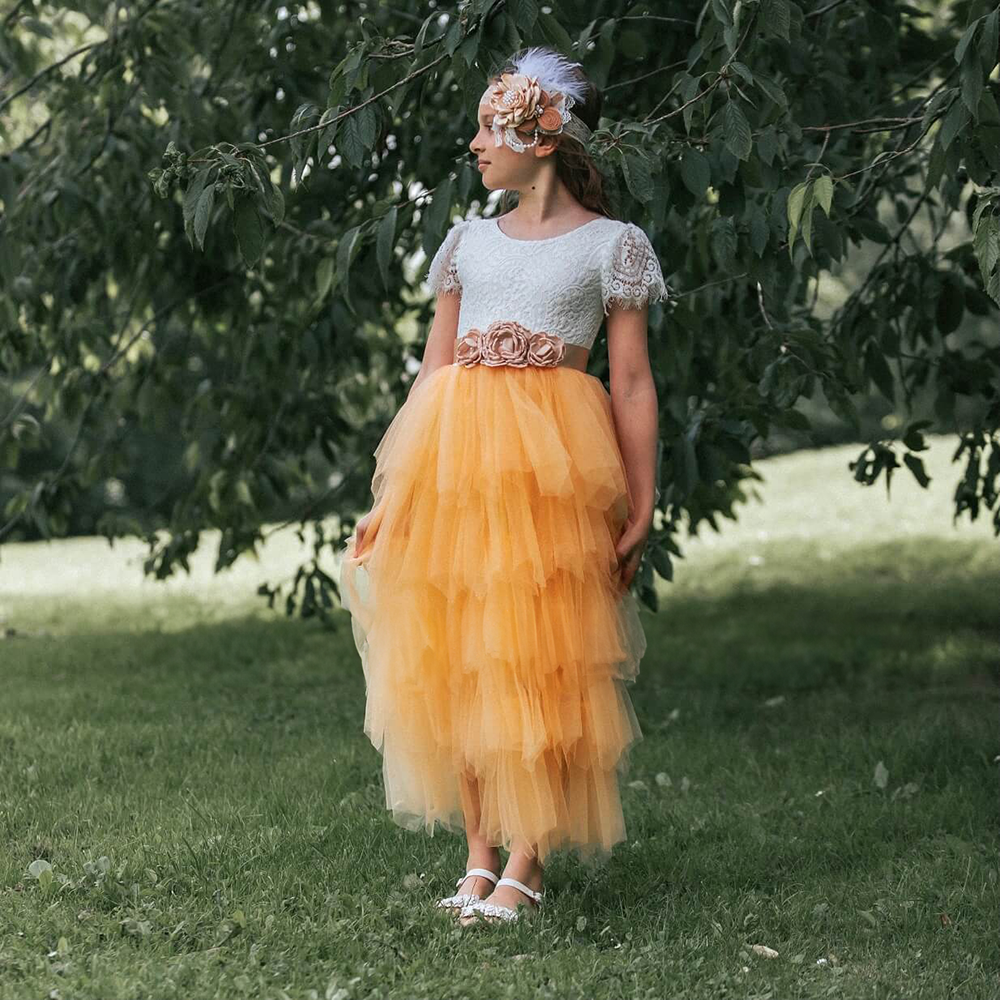 Flower Girl standing by trees wearing a yellow and cream dress