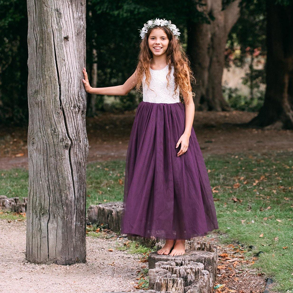 Girl wearing purple flower girl dress in a park