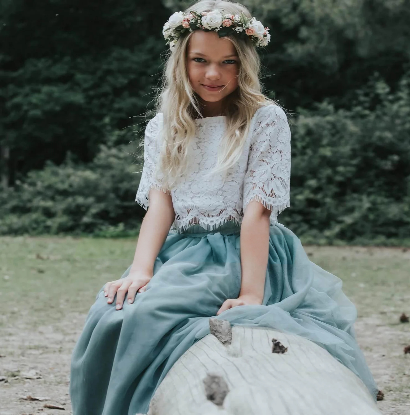 Flower girl in forest sitting on a log