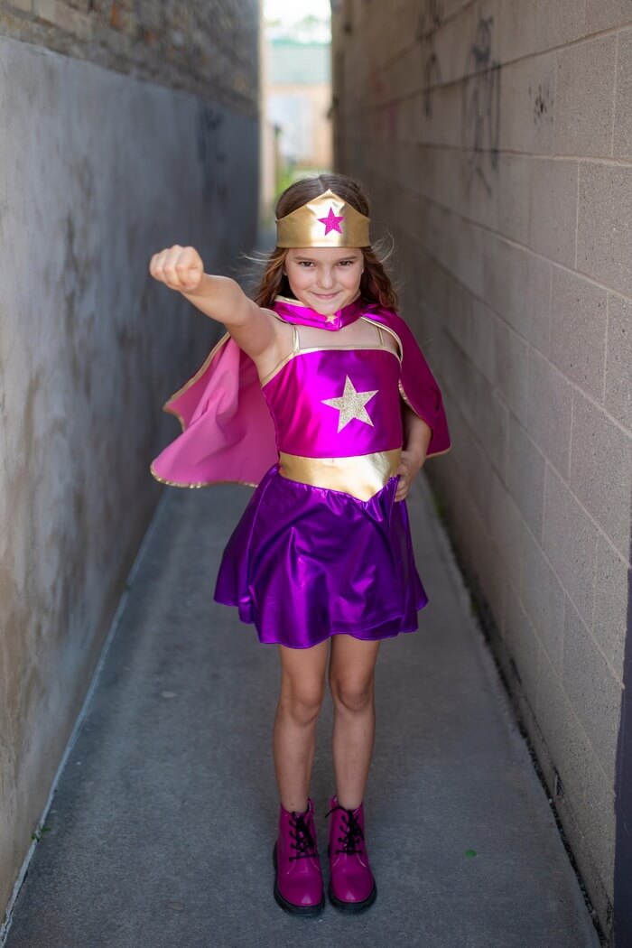 young girl playing dress up as superhero