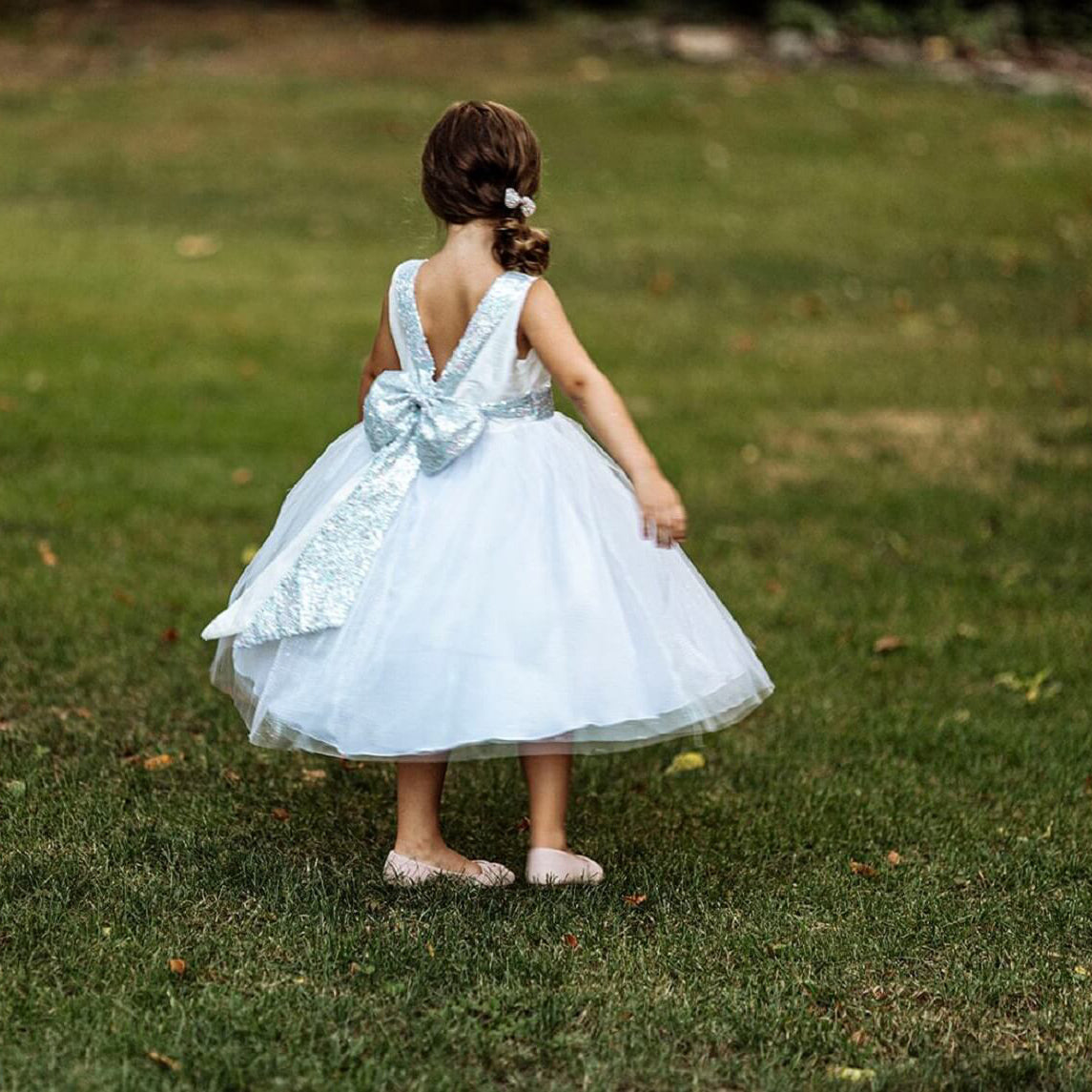 Girl standing on grass in silver flower girl dress