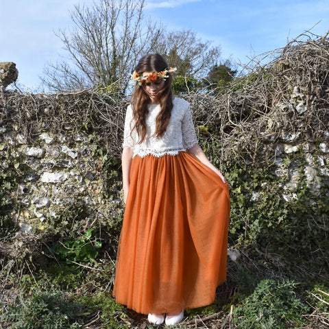 Girl standing by fence holding skirt