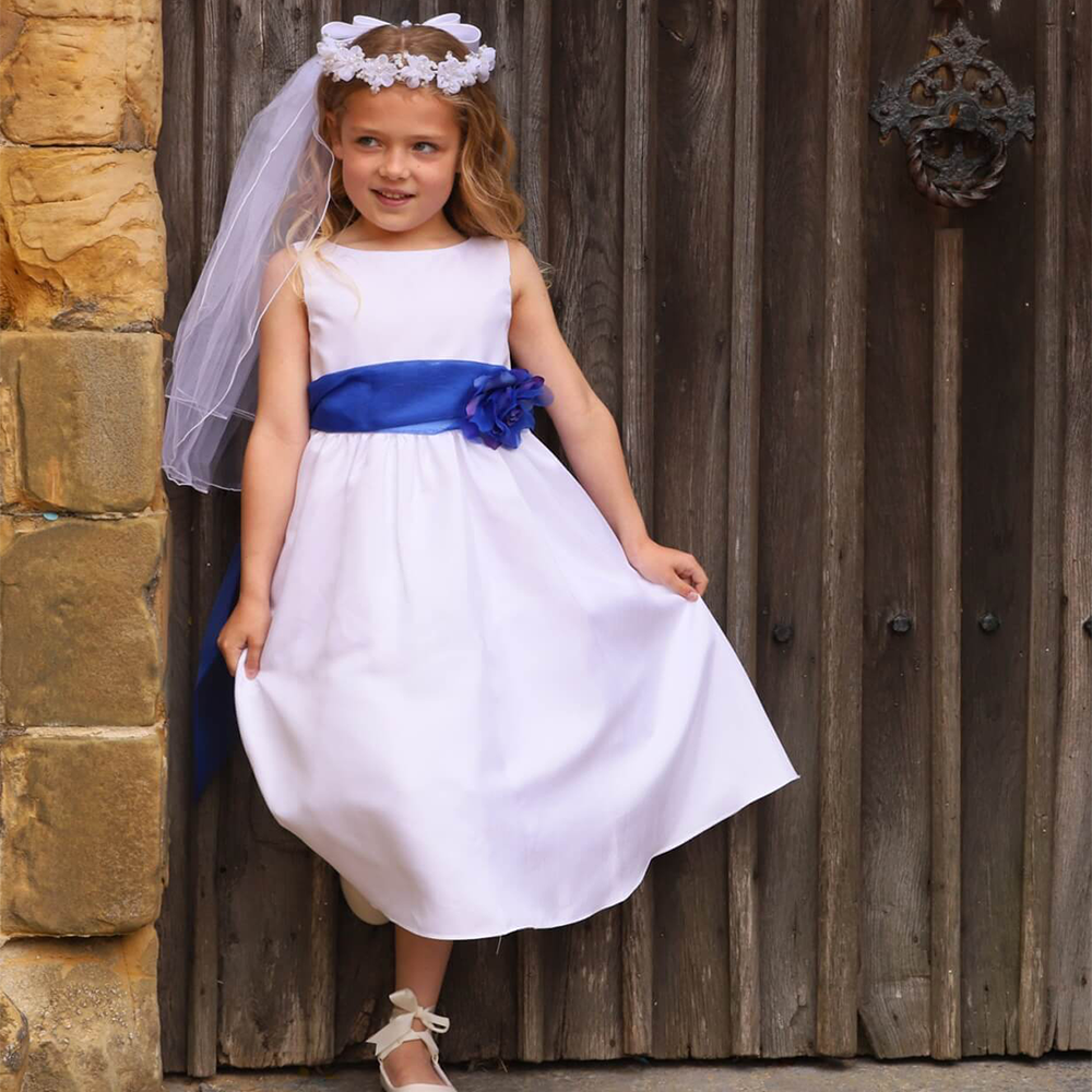 flower girl wearing a white dress with a blue bow outside a church